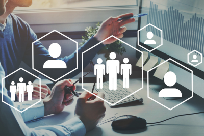 A picture of People gathered around a table working on a project with white graphics overlayed of people